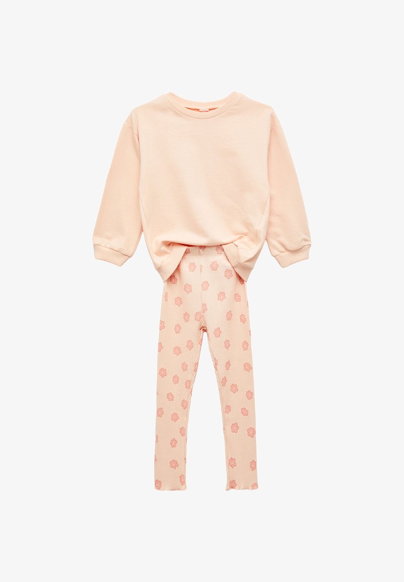 Miękki brzoskwiniowy sweter z długim rękawem w zestawieniu z prążkowanymi legginsami w różowy kwiatowy wzór, zaprezentowany na białym tle.