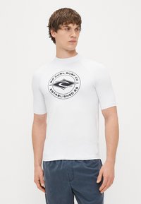 Biała koszulka z krótkim rękawem, z okrągłym czarnym logo na środku, wykonana z gładkiego, elastycznego materiału dla komfortu.