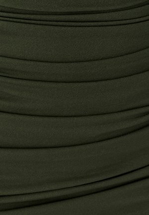 Zelená strukturovaná tkanina s horizontálními sklady, měkký elastický materiál a hladký povrch, vhodná pro oděvní aplikace.