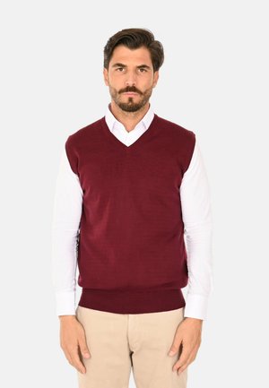 Gilet a maglia bordeaux con scollatura a V, indossato sopra una camicia bianca con colletto, caratterizzato da un orlo a coste e una vestibilità strutturata.