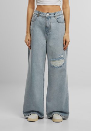 Jeans de mezclilla de tiro alto en un azul claro, con perneras anchas y detalles desgastados, además de bordes deshilachados. Cuenta con dos bolsillos frontales.