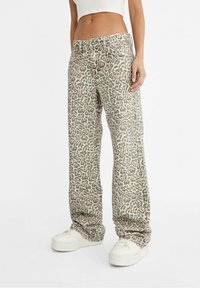 Pantalons en imprimé léopard beige et noir, fabriqués dans un tissu à la texture lisse, présentant une coupe décontractée et une taille mi-haute.