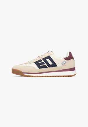 Zapatilla deportiva beige con detalles en azul marino, parte superior de ante texturizado y malla, suela de goma y lengüeta en el talón color burdeos, con un logotipo destacado en el lateral.