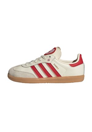 Baskets Adidas Samba blanches et rouges avec semelle en gomme, trois bandes rouges et bout en daim, vues de côté sur fond blanc.