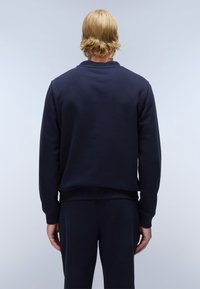 Marineblauwe sweatshirt van zachte stof met ribgebreide manchetten en onderzoom. Heeft een klassieke ronde hals en een losse pasvorm, weergegeven vanaf de achterkant.
