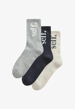 Drei Paar gerippte Knöchelsocken in Grau, Schwarz und Beige, jeweils mit dem Wort "self." vertikal nahe dem oberen Rand.