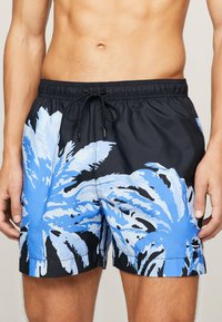 Costume da bagno neri con grandi motivi di foglie di palma blu. Vita elastica con cordino. Materiale leggero e ad asciugatura rapida.