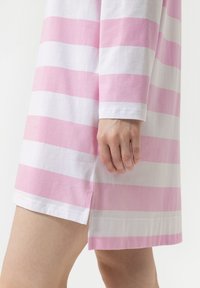 Gestreepte jurk in roze en witte katoen, met lange mouwen, een zijspleet en een zoom met zichtbare stiksels.