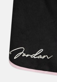 Černá látka s jemnou texturou má vyšitý nápis "Jordan" ve stříbrném písmu. Růžový saténový lem podtrhuje okraj.