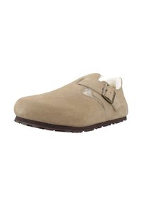 Zapato slip-on de ante beige con punta redonda, correa ajustable y cálido forro de pelo. Presenta una suela de goma texturizada para mayor tracción.