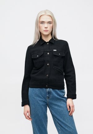 Sort denimjakke med krave, to brystlommer med klapper og metalknaplukninger. Tætsiddende design, struktureret stof.