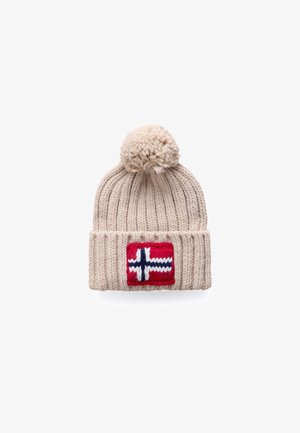 Gorro de punto beige con un pompón en la parte superior, que presenta un parche rojo con un diseño de cruz blanca y azul en el borde doblado.