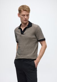 Īsām piedurknēm polo krekls teksturētā dūmakainā krāsā ar melnu apkakli un aprocēm, ar V veida kakla izgriezumu un brīvu piegriezumu.