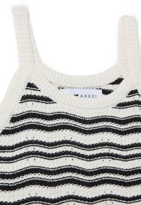 Top de punto sin mangas con rayas onduladas en crema y negro, con tirantes anchos y escote acanalado. Etiqueta con la palabra "ANGEL" visible.