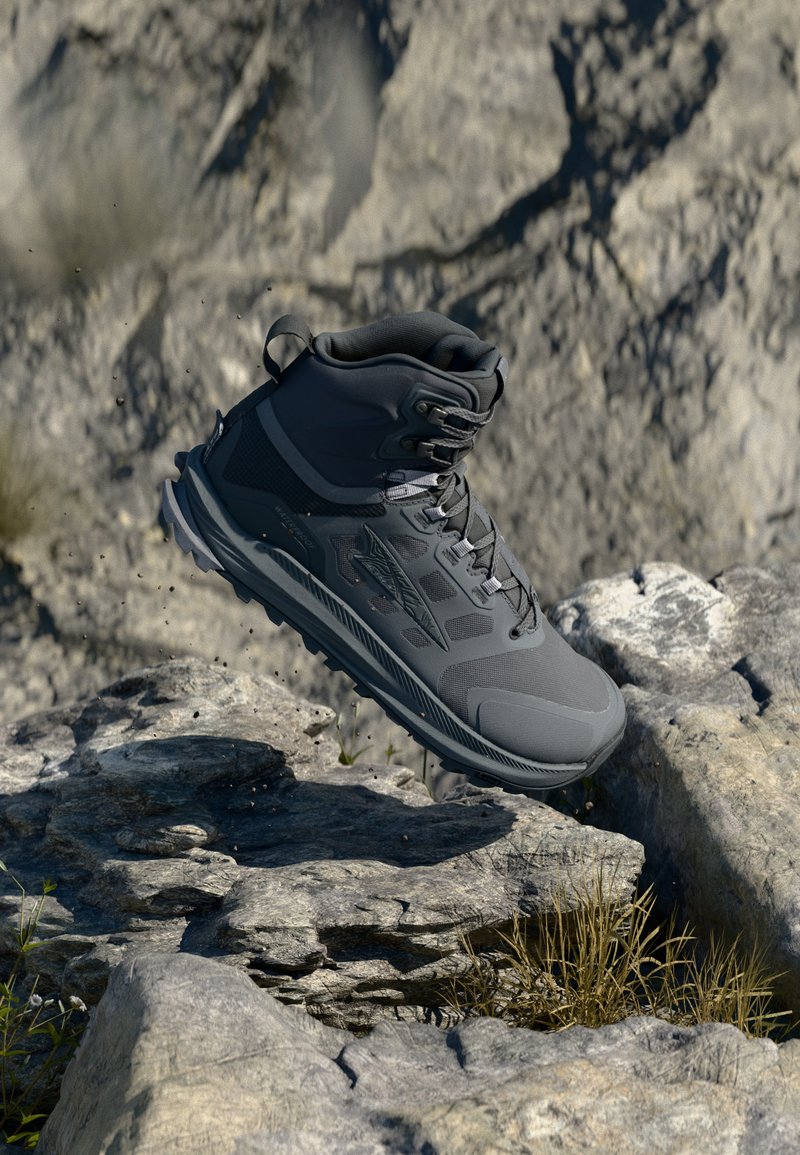 Bota alta para exteriores em cinza escuro, apresentando uma superfície texturizada, painéis de malha e um design com atacadores, com hardware reforçado para terrenos acidentados.