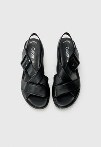 Sandales en cuir noir avec des brides entrecroisées, un accent de boucle et une semelle texturée. Marque "Gabor" visible sur le rembourrage.