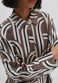 Langärmliges Button-Up-Hemd mit geometrischem Muster in Braun, Creme und Marineblau. Glatter Stoff mit klassischem Kragen und taillierter Passform.