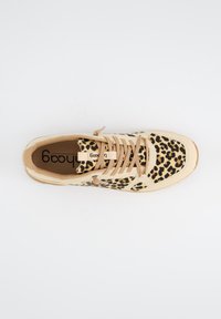 Zapatillas de leopardo con parte superior de textil beige, puntera redondeada, cordones planos y suela de goma. El interior presenta un forro marrón claro y un logo.