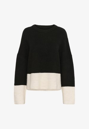 Pull color-block noir et crème avec un col rond, des manches longues et une coupe ample. Fabriqué en matériau tricoté doux et texturé.
