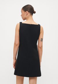 Črna brezrokavna obleka s kvadratnim izrezom, krojem, ki se prilega telesu, in zadrgo na hrbtu. Gladka tekstura z ravnim robom.