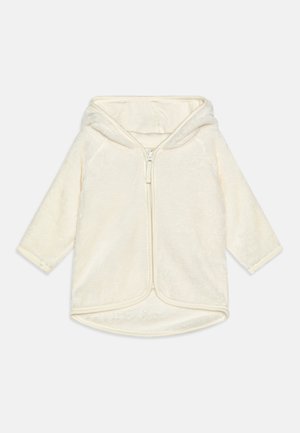 Giacca felpata con cappuccio di colore crema, caratterizzata da una cerniera frontale, maniche lunghe e orlo arrotondato con tessuto morbido e testurizzato.