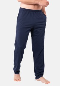 Pantalons bleu marine à coupe décontractée en tissu doux, dotés d'une taille élastique et de poches latérales, avec une texture lisse et sans motifs visibles.
