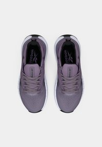 Sapatilhas atléticas roxas com parte superior em malha, bico arredondado e sola branca. Apresenta atacadores, colarinho acolchoado e logotipo da Reebok na palmilha preta.