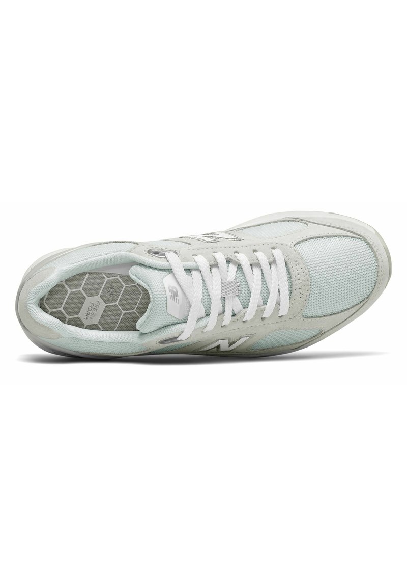 Zapatilla deportiva en gris claro y blanco con paneles de malla, cordones blancos y plantilla con patrón hexagonal etiquetada como "FRESH FOAM".