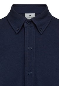 Dunkelblaue Button-Up-Bluse mit klassischem Kragen, glatter Textur und drei schwarzen Knöpfen an der Vorderseite. Etikett im Kragen sichtbar.