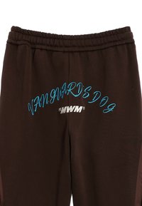 Pantalones de chándal marrones con texto bordado en azul y plata que dice "VANGUARD'S DOG" y "MWM", con una cinturilla elástica para mayor comodidad.