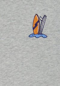 Un tessuto grigio presenta un piccolo design ricamato di una tavola da surf gialla con un fulmine blu, parzialmente immersa in acqua blu.
