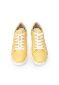 Sneakers in pelle gialla con lacci bianchi. Forma della punta arrotondata, tomaia testurizzata e suola in gomma bianca. Design minimalista senza loghi visibili.