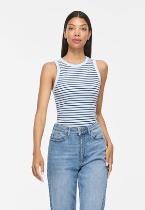 Femme portant un haut sans manches bleu clair avec des rayures horizontales bleu foncé et un jean bleu clair taille haute sur fond blanc.