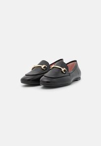 Mustad nahast loafers särava pinnaga, terava nina ja kullatoonilise metallist detailiga üle vammuste, mille sees on sile vooder.