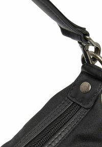 Sac en tissu noir au toucher lisse, avec une fermeture éclair en métal et un accent de bouton-pression. Comprend une bandoulière robuste.