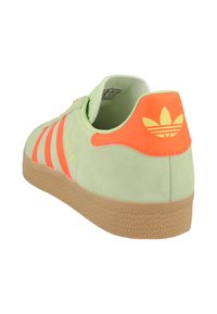 Ljust grön mocka sneaker med klara orange detaljer. Har tre ränder, vadderad häl och texturerad tan gummisula.