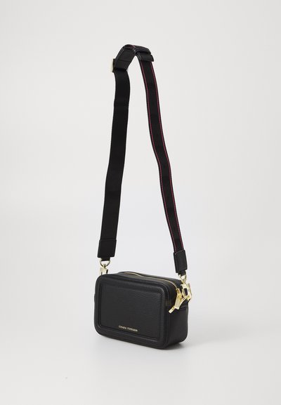 Borsa a tracolla in pelle nera con texture, forma rettangolare, hardware con zip dorata e tracolla regolabile con accento rosso.