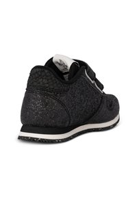 Sneaker nera con una tomaia testurizzata e leggermente glitterata, cinturini in Velcro e una suola bianca maculata per un contrasto aggiuntivo.