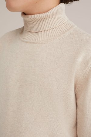 Svetar s turtleneck ovratnikom v svetlo bež barvi, z rebrastim ovratnikom in mehkobo; ima ožji kroj in brezšivno zasnovo za čist videz.