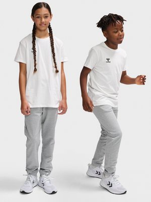 To børn iført hvide hummel t-shirts, grå joggers og hvide sneakers, hvor den ene står stille, og den anden er midt i et skridt.