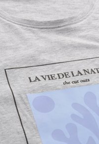Grå bomullströja med rund halsringning, tryckt design med blå abstrakta former och text i svart: "LA VIE DE LA NATURE the cut outs."