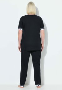 Zwarte loungewear set met een top met korte mouwen en kanten rand aan de mouwen, en bijpassende broek, beide in een zachte stof.
