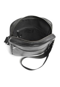 Černá kožená crossbody taška se zipovým uzávěrem, vnitřní kapsou, textilním podšíváním a nastavitelným popruhem.