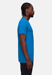 Niebieska koszulka sportowa z krótkim rękawem z lekkiego materiału, z okrągłym dekoltem i minimalnym logo na piersi, w połączeniu z czarnymi szortami.