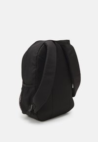 Zaino nero con corpo in tessuto morbido e lati in rete traspirante. Presenta spallacci imbottiti e una forma rettangolare slanciata.