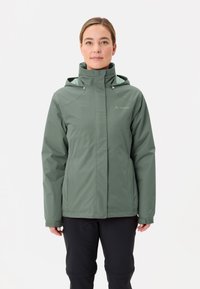 Giacca impermeabile verde con cappuccio, dotata di chiusura con zip e polsini regolabili. La fodera interna è azzurra chiara con una texture liscia.