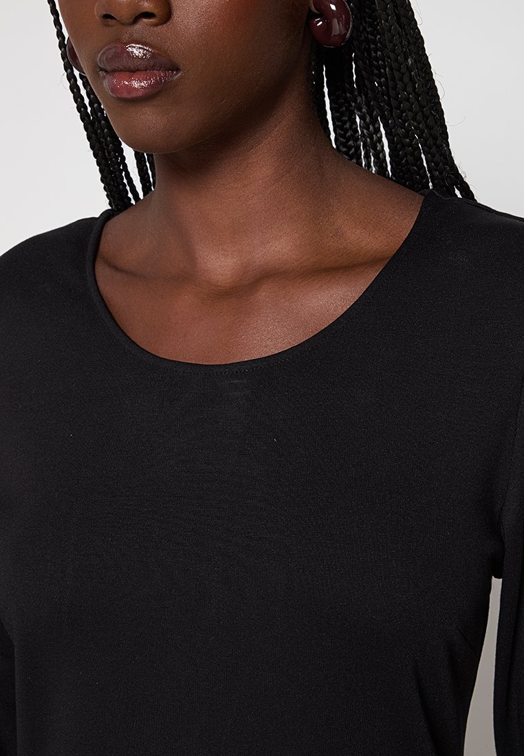 Czarny top z długim rękawem i okrągłym dekoltem, wykonany z gładkiego materiału o dopasowanym kroju. Widoczny kolor skóry i warkocze.