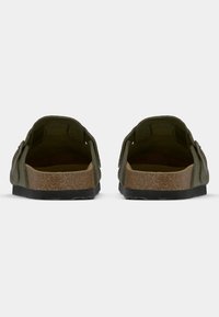 Olivgrüne Sandalen mit einem Korkfußbett und schwarzen Gummisohlen, mit offenen Fersen und verstellbaren Riemen für zusätzlichen Komfort.