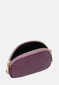 Fioletowa skórzana portmonetka o zaokrąglonym kształcie, złoty zamek błyskawiczny oraz wytłoczone logo w środku. Gładka tekstura z elegancko kompaktowym designem.