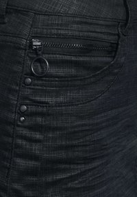 Černé džíny s přední kapsou se zipem, kulatým zipem na stahování a pěti knoflíkovými zapínáními na pase, strukturovaný vzor látky.